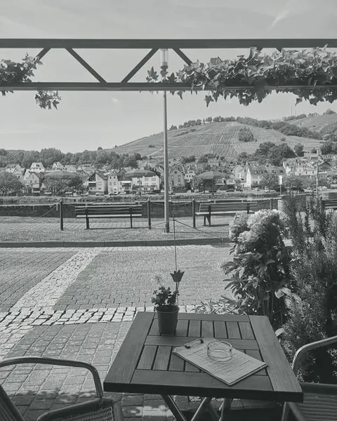 Tisch auf einer Terrasse mit Blick über die Uferpromenade auf die Weinberge an der Mosel