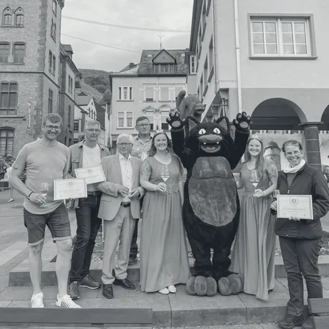 Gruppe mit Urkunden und dem schwarzen Katzenmaskottchen beim Weinfest in Zell