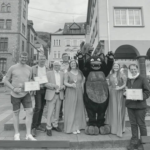 Gruppe mit Urkunden und dem schwarzen Katzenmaskottchen beim Weinfest in Zell